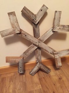 a wooden snowflake sitting on top of a hard wood floor next to a wall