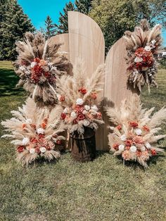 three wooden boards with flowers and feathers on them in the middle of grass next to trees