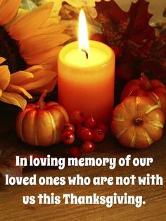 a candle and some pumpkins are sitting on a table next to sunflowers