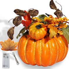 an orange pumpkin decorated with leaves and berries