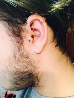 a man with some piercings on his ear and behind his ear is a small piece of hair