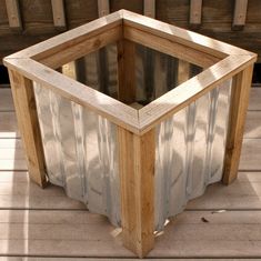 a wooden box sitting on top of a wooden floor next to a fence and wood planks