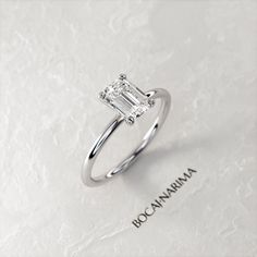 an engagement ring with a baguette cut diamond set in the center on a white background