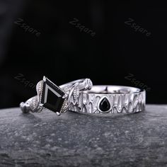 two silver rings with black stones on them sitting on top of a stone slab in the dark