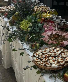 a table topped with lots of different types of food on top of tables covered in white cloths