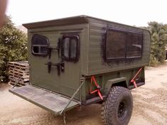 an army green truck parked on top of a dirt road