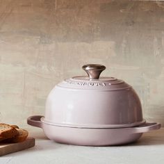 a white pot and some bread on a table