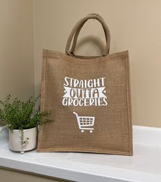 a burlap shopping bag sitting on top of a shelf next to a potted plant