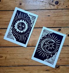 two black and white cards with sun and moon designs on them sitting on a wooden floor