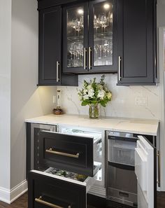 a kitchen with black cabinets and white marble counter tops, an icebox in the center