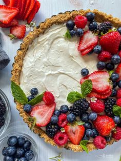 a pie with strawberries, blueberries and raspberries on it next to other desserts