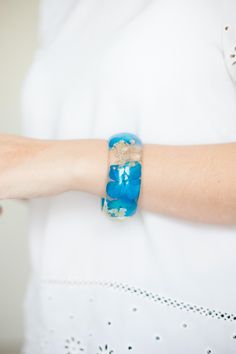 Real pressed flower resin bangle. The bangle features blue hydrangea flowers, and white baby's breath flowers. The bangle is made with jeweler's grade resin.  Available in 3 sizes: Small: diameter/opening 2.4" (63mm) , height of the bracelet is approximately 1" (25mm) Medium: diameter/opening 2.6" (66mm) , height of the bracelet is approximately 1" (25mm) Large: diameter/opening 2.72" (69mm) , height of the bracelet is approximately 1" (25mm) XS and XL sizes available upon request. If you are unsure if it will fit you, please feel free to contact us and we will send you instructions on how to measure your hand and see if this bangle size will fit.  We have partnered with the National Forest Foundation, and we are planting one tree for every bracelet sold. Blue Resin Bracelets Perfect For Gifts, Blue Resin Bracelets For Gift, Blue Resin Bracelets As Gifts, Blue Resin Bracelets For Gifts, Resin Bangle Jewelry Gift, Resin Bangle Jewelry For Gifts, Blue Hypoallergenic Bangle Jewelry, Adjustable Resin Bangle Jewelry, Adjustable Resin Jewelry With Pressed Flowers