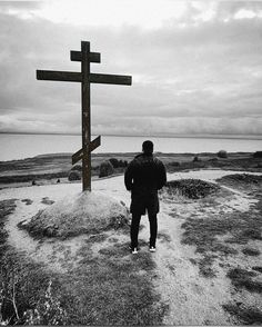 a man standing in front of a cross on top of a hill