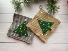 two crocheted christmas ornaments sitting on top of a wooden table next to pine branches