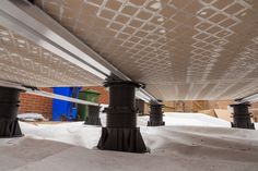 the underside of a building with snow on the ground and metal poles sticking out from underneath