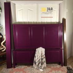 a cat laying on the floor in front of a purple headboard and foot board