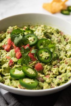 a white bowl filled with guacamole and green peppers