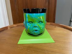 a green and blue cup sitting on top of a wooden table