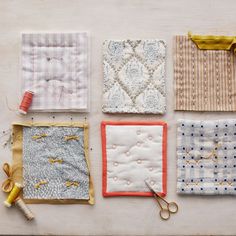 four different quilts are laid out on a table with thread, scissors and spools