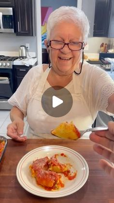 an older woman is eating lasagna in the kitchen