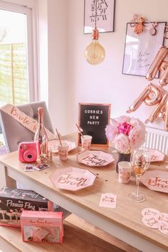 the table is set up with pink and gold decorations, wine glasses, champagne bottles, and other items