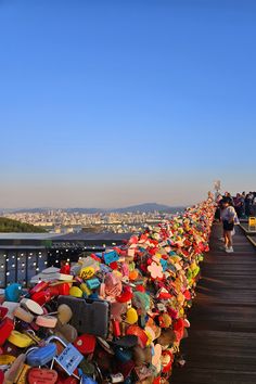 many hats are lined up along the edge of a bridge with people walking on it