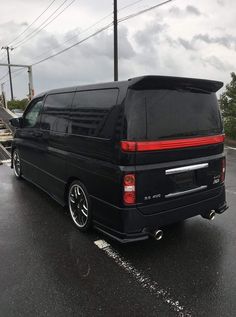 the back end of a black van parked in a parking lot