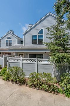 a large gray house with lots of windows on the front and side of it, surrounded by greenery