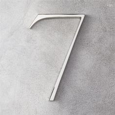 the number seven is made out of metal and sits on a gray surface with no one around it