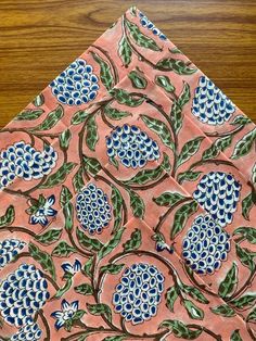 a piece of cloth with blue and green designs on it sitting on a wooden table