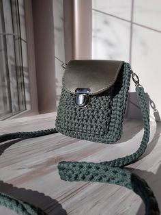 a crocheted purse sitting on top of a wooden table next to a window