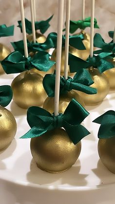 gold and green cake pops with bows on a white platter, ready to be eaten