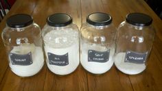 three glass jars with labels on them sitting on a table