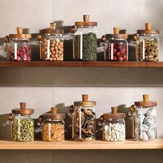 several jars filled with different types of food on top of a wooden shelf next to each other