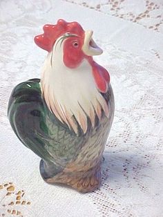 a rooster figurine sitting on top of a white table cloth covered tablecloth