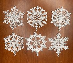 four snowflakes are shown on a wooden surface