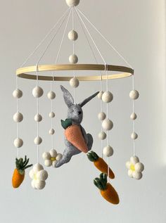 a stuffed rabbit hanging from the ceiling with carrots on it's legs and feet