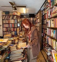 a woman standing in front of a book shelf filled with books