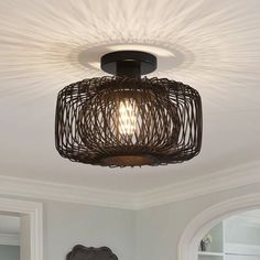 a light that is hanging from the ceiling above a bed in a room with white walls