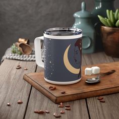 a coffee mug sitting on top of a wooden table next to a spoon and cup