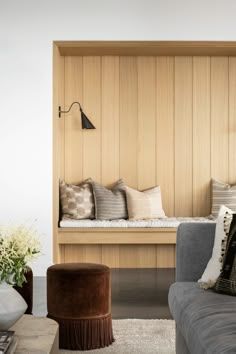 a living room filled with furniture and wooden paneling on the wall next to a window