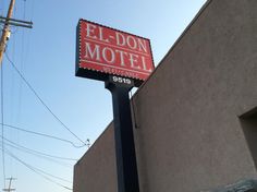 an el - don motel sign in front of a gray building with red lettering on it