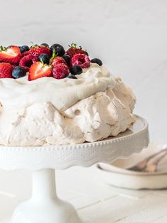 a white cake topped with berries and whipped cream