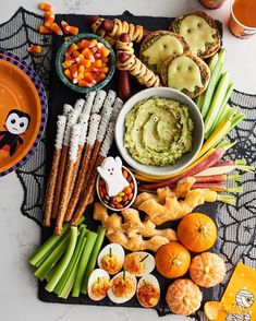 an assortment of halloween foods and snacks on a table with oranges, candy sticks, crackers, pumpkins