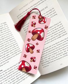 a bookmark with red mushrooms on it and a tassel hanging from the front