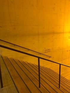 a yellow light shines on the side of a building with metal handrails