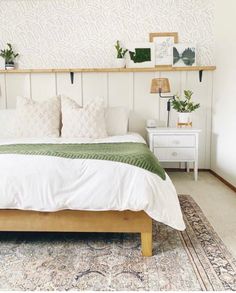 a bed with white sheets and pillows in a bedroom next to a wall mounted planter