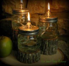 three mason jars with candles in them sitting on top of a tree stump next to an apple