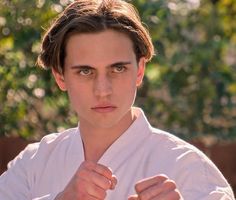 a young man wearing a white shirt and pointing his finger at the camera