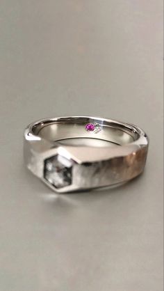 a close up of a wedding ring with a pink diamond in it on a table